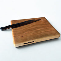 Small cherry cutting board by Treeboard with knife. Elegant chopping board with a white background. The black cherry is a "gummy" or "heavy gum" cherry.