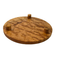 Round trivet seen from below. A cherry stand for hot pans with three legs, by Treeboard. Photo shows curly cherry grain.