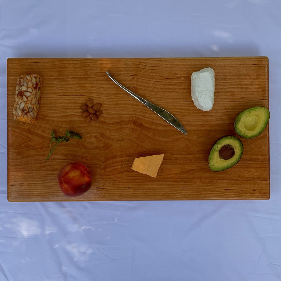 Large black cherry serving board and cutting board or cheese board by Treeboard with avocado, knife, chevre, goat cheese.