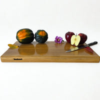 Large white oak chopping board by Treeboard with apple and squash and a knife.