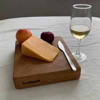 Small white oak cutting board by Treeboard with a glass of white wine, cheese, nectarine, plum and table knife.
