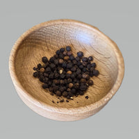 Black pepper corns in a handmade oak spice bowl by Treeboard.