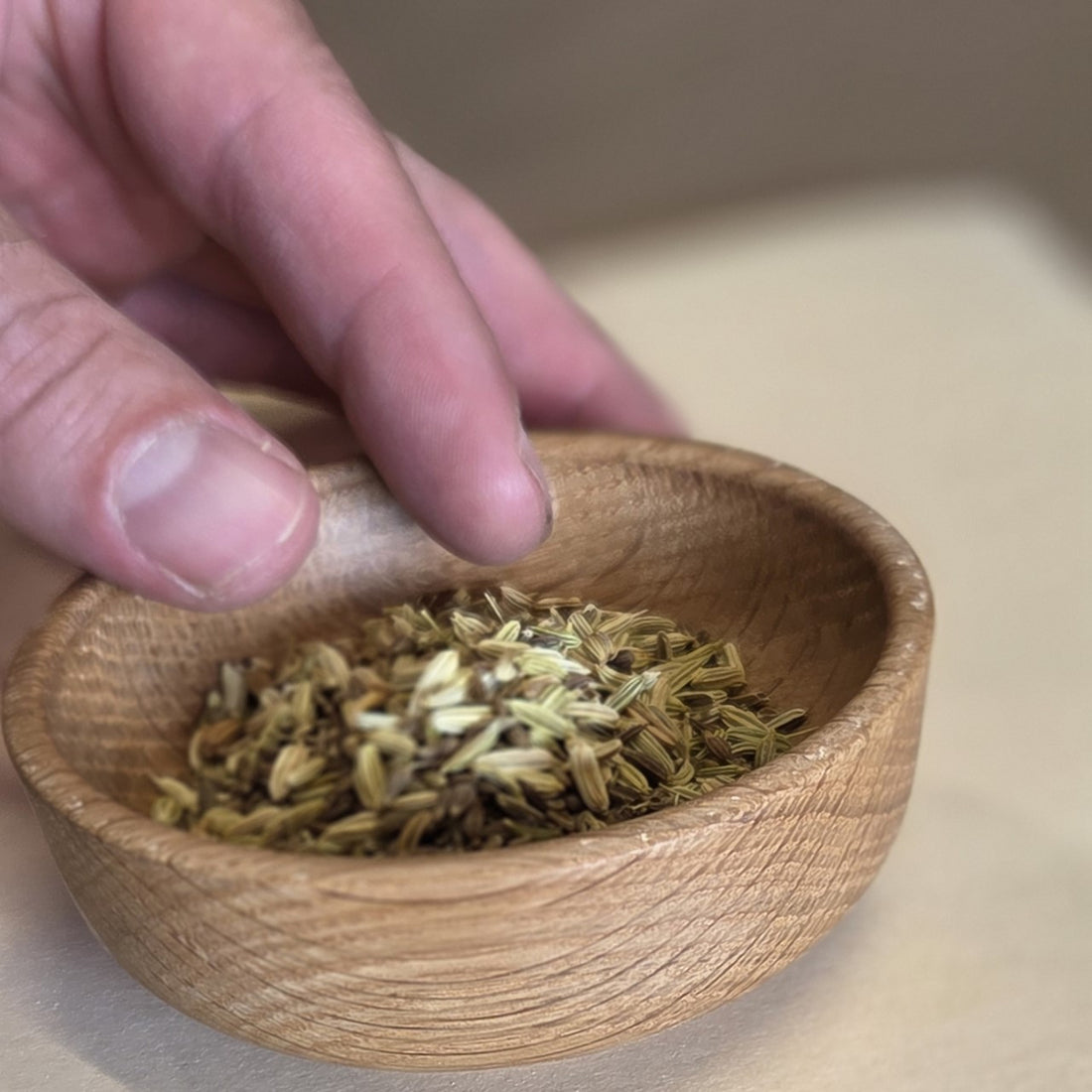 Handmade wooden bowl by Treeboard with hand and fennel seeds inside the bowl.