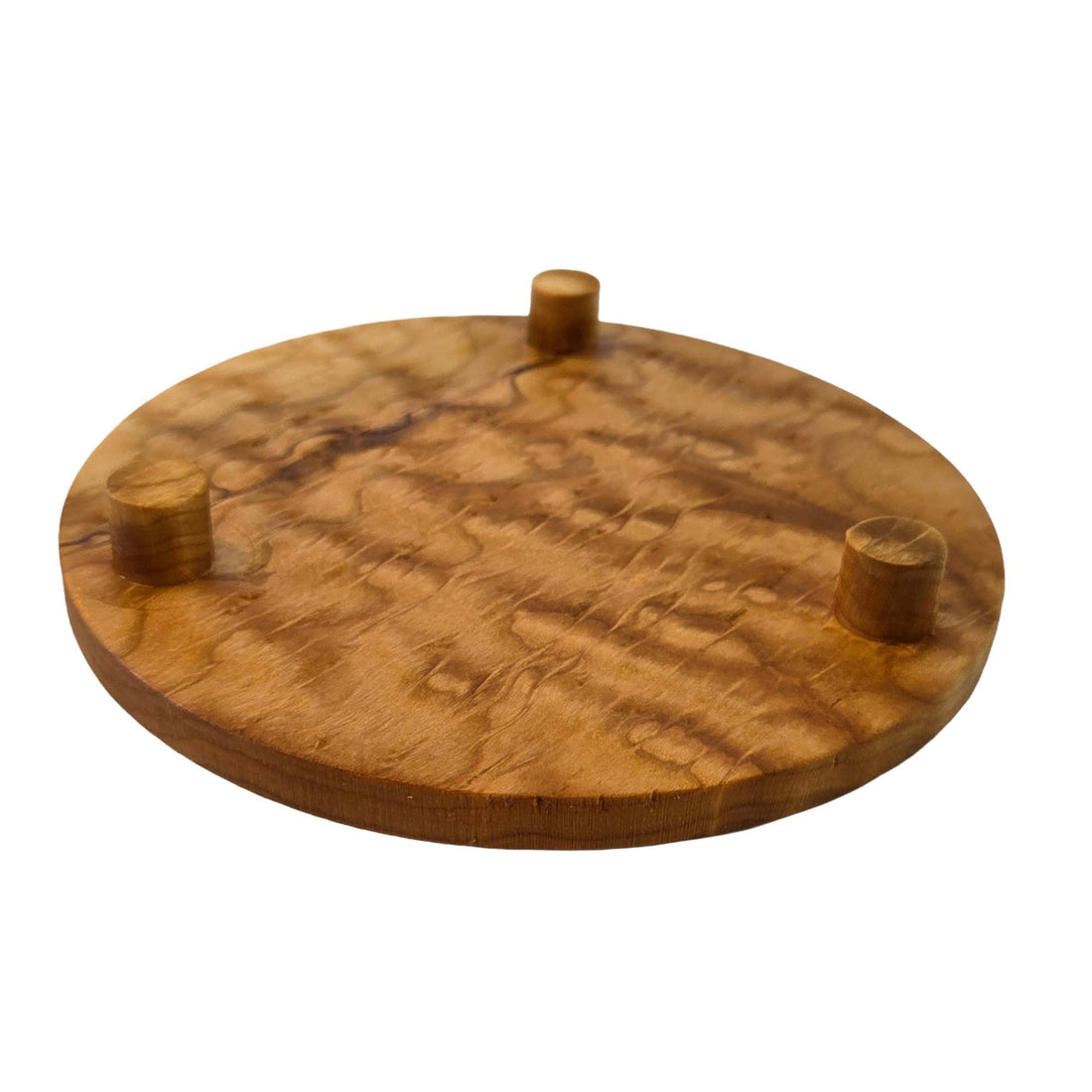 Round trivet seen from below. A cherry stand for hot pans with three legs, by Treeboard. Photo shows curly cherry grain.