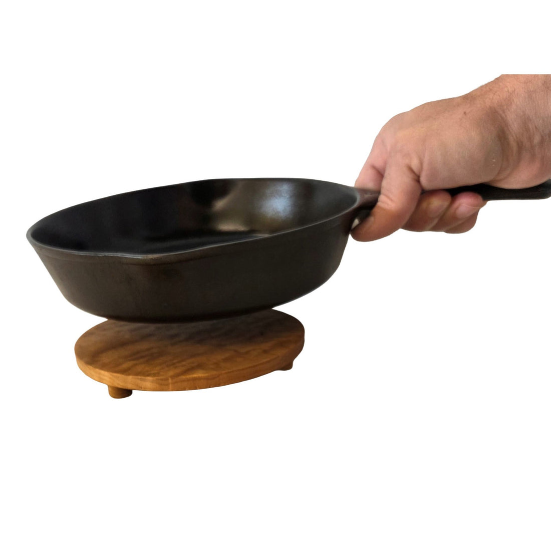 Round cherry wood trivet by Treeboard with cart-iron pot held by a man&