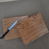 Two small cherry cutting boards by Treeboard with a knife on brown paper. Elegant chopping board with a white background. The black cherry is a "gummy" or "heavy gum" cherry.