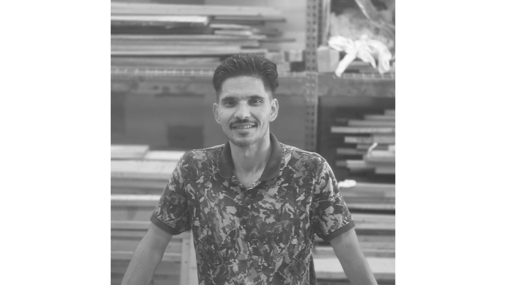 Naqib in the Workshop Treeboard woodworker Naqib stands at his workbench with hardwood lumber in the background.